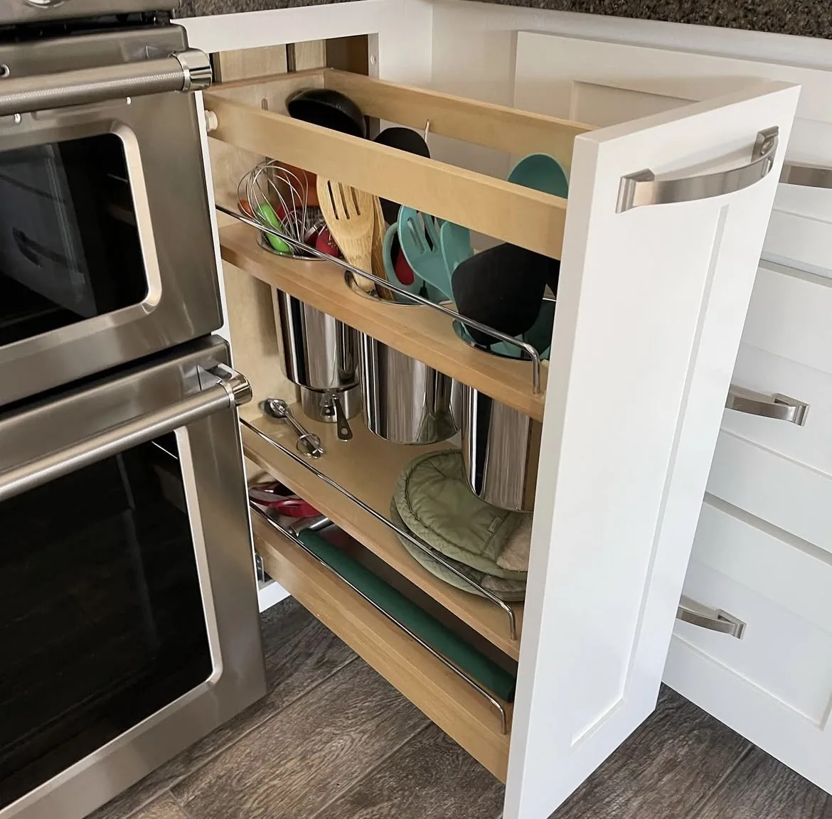 Custom pull-out cabinet organizer beside a double wall oven in a kitchen remodel by Orange Cactus Remodeling